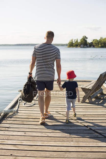 Rear view of father and son on jetty — Stock Photo