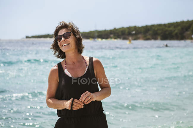 Femme souriante à la plage, se concentrer sur le premier plan — Photo de stock