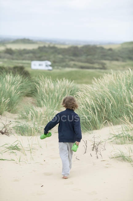 Vue arrière du garçon marchant sur la plage au Danemark — Photo de stock