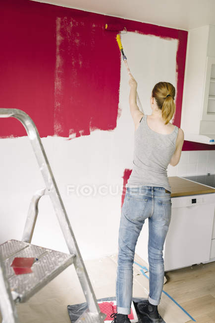 Женщина рисует стену на кухне, избирательный фокус — стоковое фото