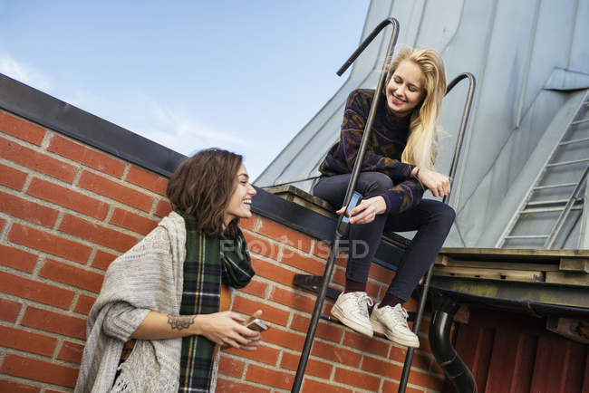 Dos mujeres jóvenes usando teléfonos inteligentes, se centran en primer plano - foto de stock