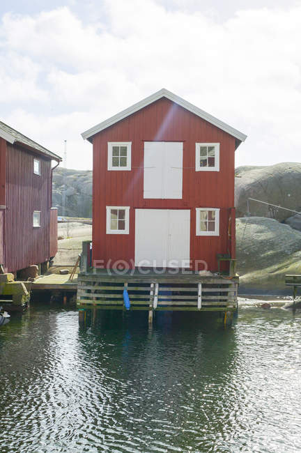 Casas vermelhas pela água contra o céu com nuvens — Fotografia de Stock