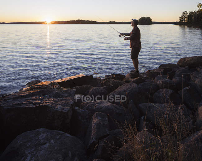 Mid adult man fishing at sunset — Stock Photo