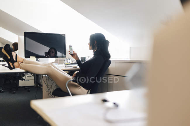 Mujer de negocios con los pies en el escritorio, enfoque selectivo - foto de stock