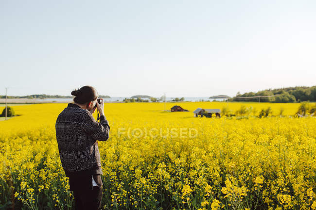 Young man taking photo of rural scene — Stock Photo