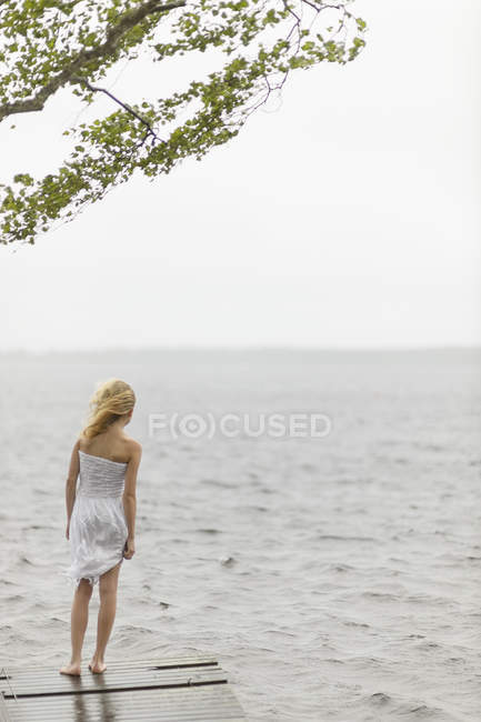 Девушка, стоящая на пристани у озера, избирательный фокус — стоковое фото
