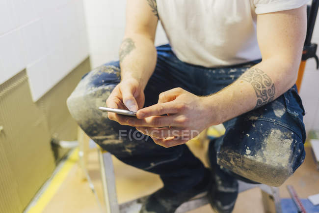 Tiler using smart phone, focus on foreground — Stock Photo