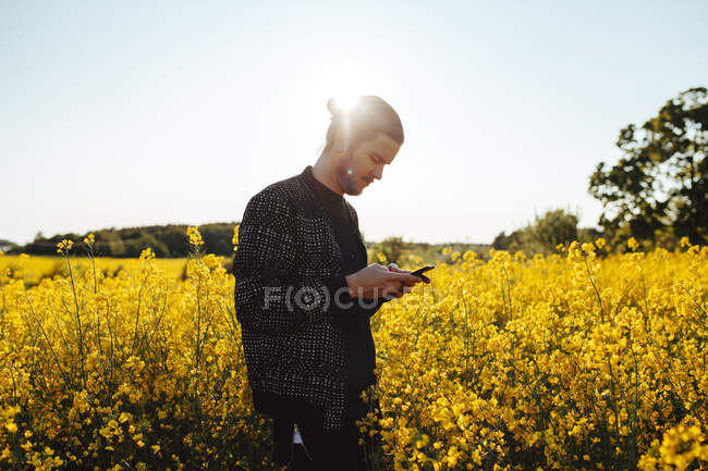 Человек на сельскохозяйственном поле с помощью смартфона — стоковое фото