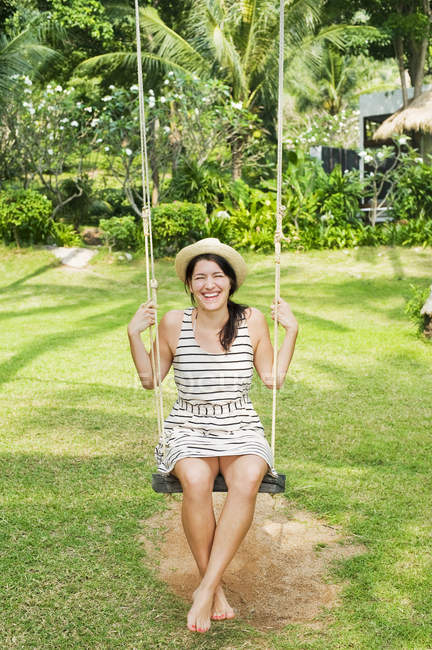 Smiling woman in sun hat on swing — Stock Photo