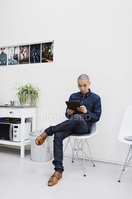 Freelancer usando comprimido digital contra parede branca — Fotografia de Stock