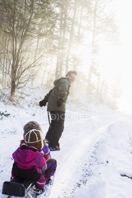 Father pulling two young daughters on sled — Stock Photo