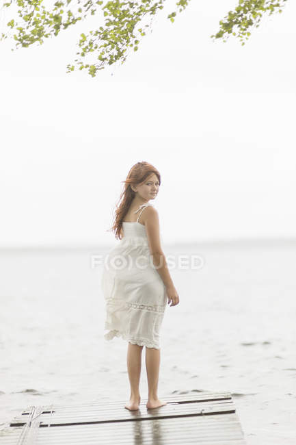 Girl standing on jetty by lake, selective focus — Stock Photo