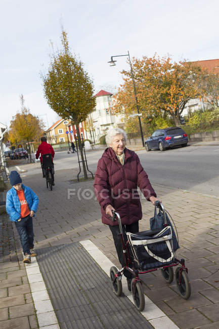 Menino andando com a avó com rolos, foco em primeiro plano — Fotografia de Stock