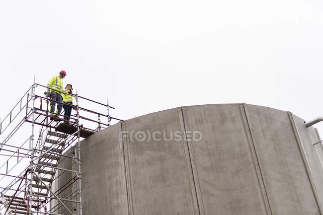 Man and woman standing on scaffolding by water treatment plants — Stock Photo