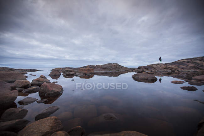 Donna in piedi vicino alla piscina rocciosa sotto cielo coperto — Foto stock