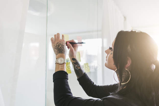 Businesswoman putting notes on window, selective focus — Stock Photo