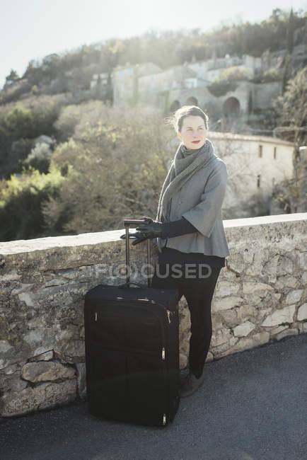 Mujer joven con maleta mirando hacia otro lado - foto de stock