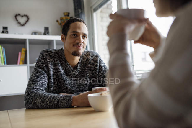 Pareja joven sentada en la mesa y tomando café, enfoque selectivo - foto de stock