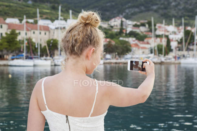 Молода жінка бере селфі, зосереджується на передньому плані — стокове фото