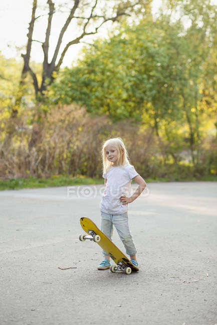 Девушка позирует со скейтбордом, сосредоточиться на переднем плане — стоковое фото