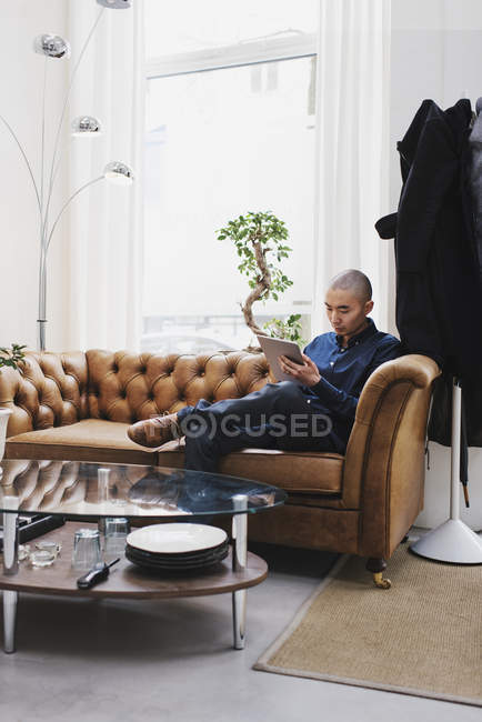 Freelancer sitting on sofa and using digital tablet — Stock Photo