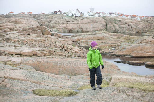 Femme debout sur la plage de rochers et regardant la vue — Photo de stock