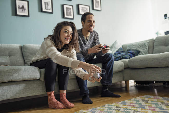 Jeune couple jouant à des jeux vidéo dans le salon — Photo de stock