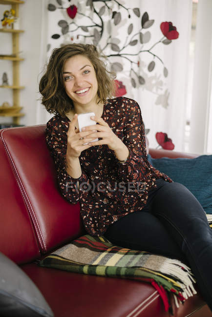 Молода усміхнена жінка використовує мобільний телефон — стокове фото