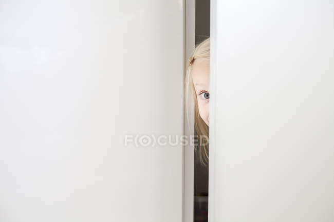 Девушка смотрит в камеру через дверь — стоковое фото