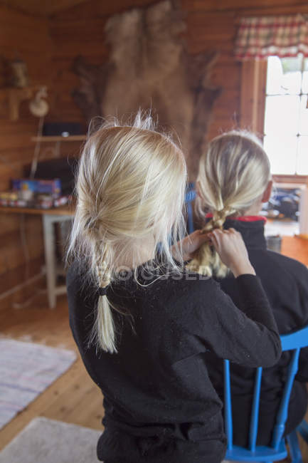 Девушка связывает матери волосы в гостиной — стоковое фото