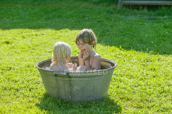 Братья и сёстры принимают ванну на заднем дворе — стоковое фото