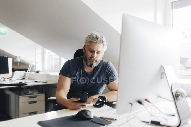 Man at office desk using smart phone, selective focus — Stock Photo
