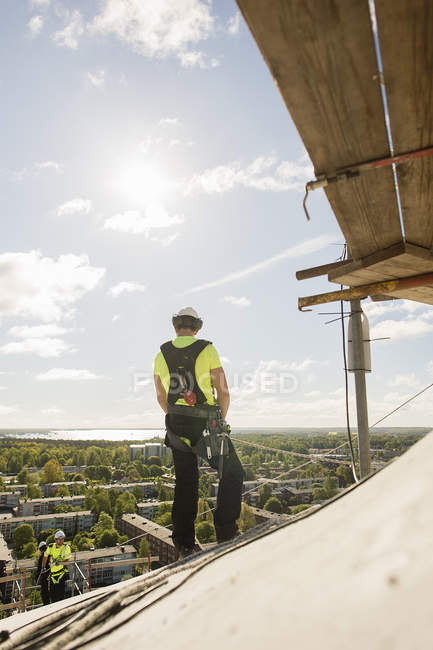Construction workers rappelling from roof, differential focus — Stock Photo