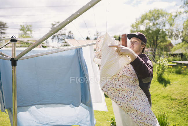 Junger Mann hängt Wäsche auf, konzentriert sich auf den Vordergrund — Stockfoto