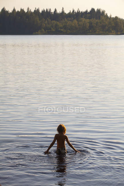 Vue arrière du garçon marchant dans l'eau — Photo de stock