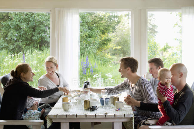 Família sentada à mesa e rindo juntos — Fotografia de Stock