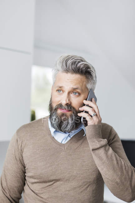 Чоловік в коричневому светрі говорить на мобільному телефоні — стокове фото