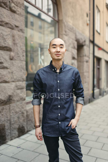 Smiling young man on sidewalk, focus on foreground — Stock Photo