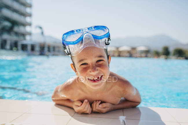 Happy boy leaning on edge of swimming pool — Stock Photo