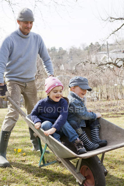Padre con hijos en carretilla, enfoque selectivo - foto de stock