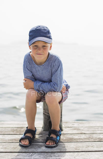 Garçon assis sur le poteau sur la jetée, foyer sélectif — Photo de stock