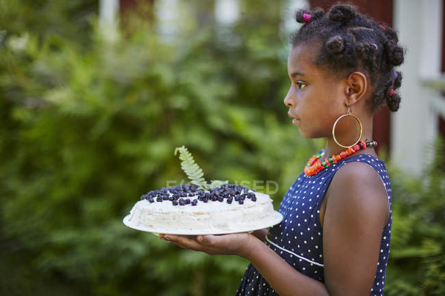 Menina segurando bolo com mirtilos, foco em primeiro plano — Fotografia de Stock