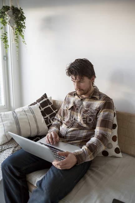 Uomo adulto medio che utilizza il computer portatile in soggiorno — Foto stock