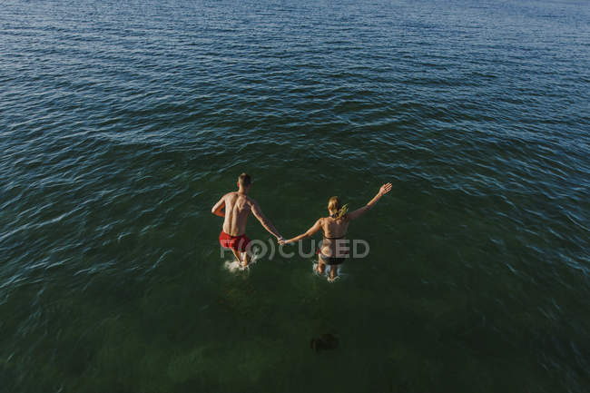 Homme et femme sautant dans la mer — Photo de stock
