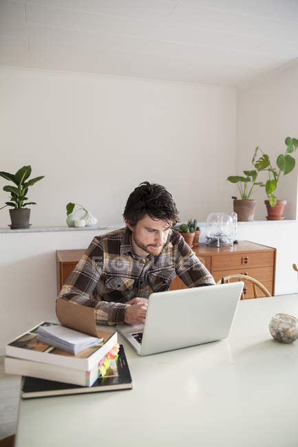 Homme adulte moyen utilisant un ordinateur portable au bureau à la maison — Photo de stock