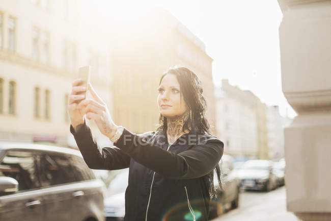 Жінка робить селфі на вулиці, фокус на передньому плані — стокове фото