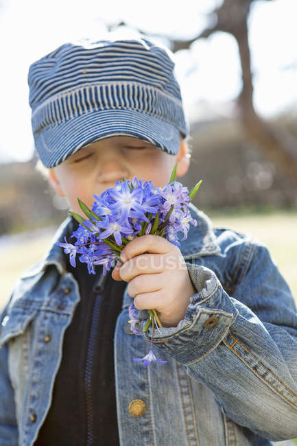 Boy smelling flowers, selective focus — Stock Photo