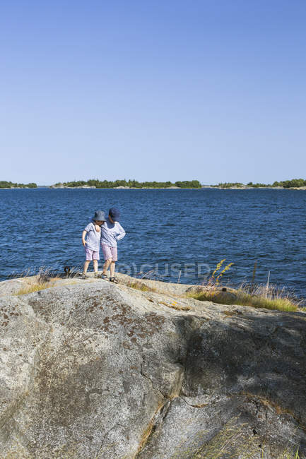 Chicos de pie en la roca en la bahía, se centran en primer plano - foto de stock