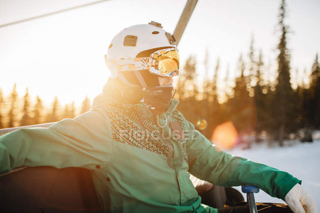 Homme portant des lunettes et un casque au coucher du soleil, se concentrer sur le premier plan — Photo de stock