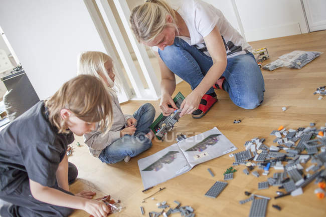 Mother playing with children in living room — Stock Photo